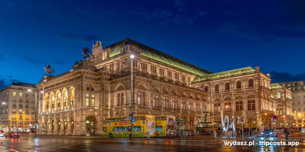 Opera Wiedeńska wieczorem, oświetlona fasada nad mokrą ulicą
